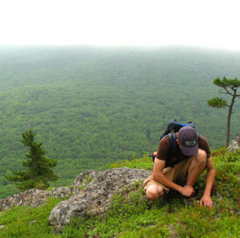 Care Omnia picture of a man looking for something on the ground with a wast scenery behind him