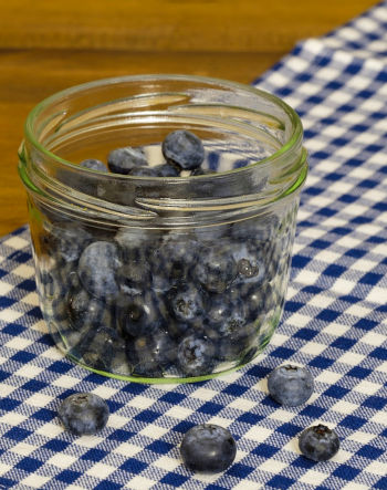 Jar with healthy blueberries on a blue-white table cloth