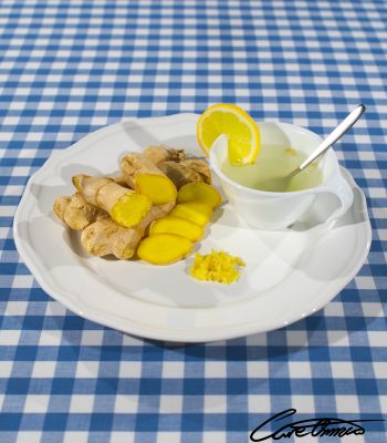 Chopped, graded ginger on a plate with a cup of ginger tea