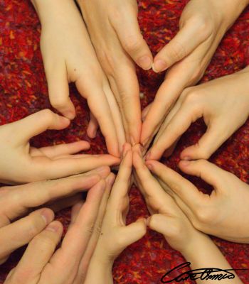 Adult and child hands forming hearts around a circle on a red carpet.