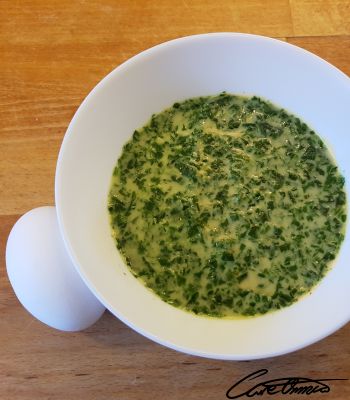 A bowl of spinach soup with a boiled egg on the side