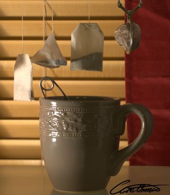A big cup of tea with some tea bags hanging above it.