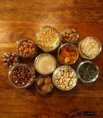 Jars with a variety of nuts, seeds etc on a wooden surface