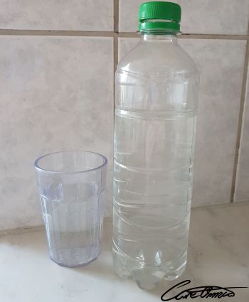 A bottle of water and glas next to it